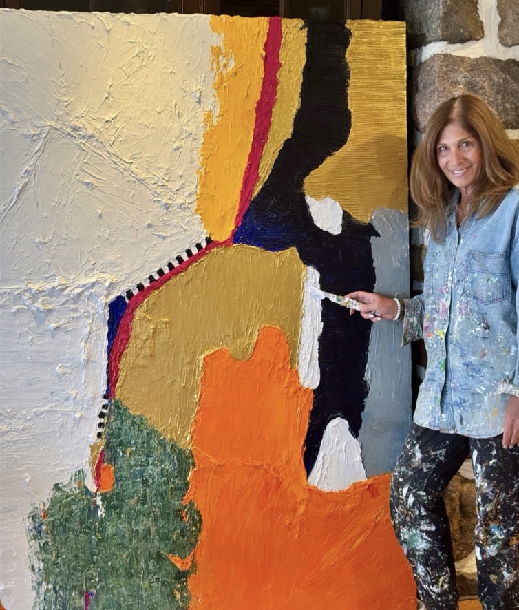 Artist Louise Courey beside her large orange and gold impasto painting