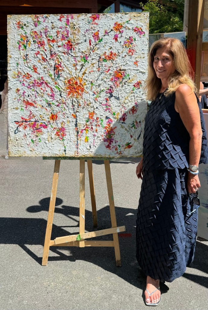 Louise Courey beside Celebrate the Moments, a sculptural white floral impasto painting